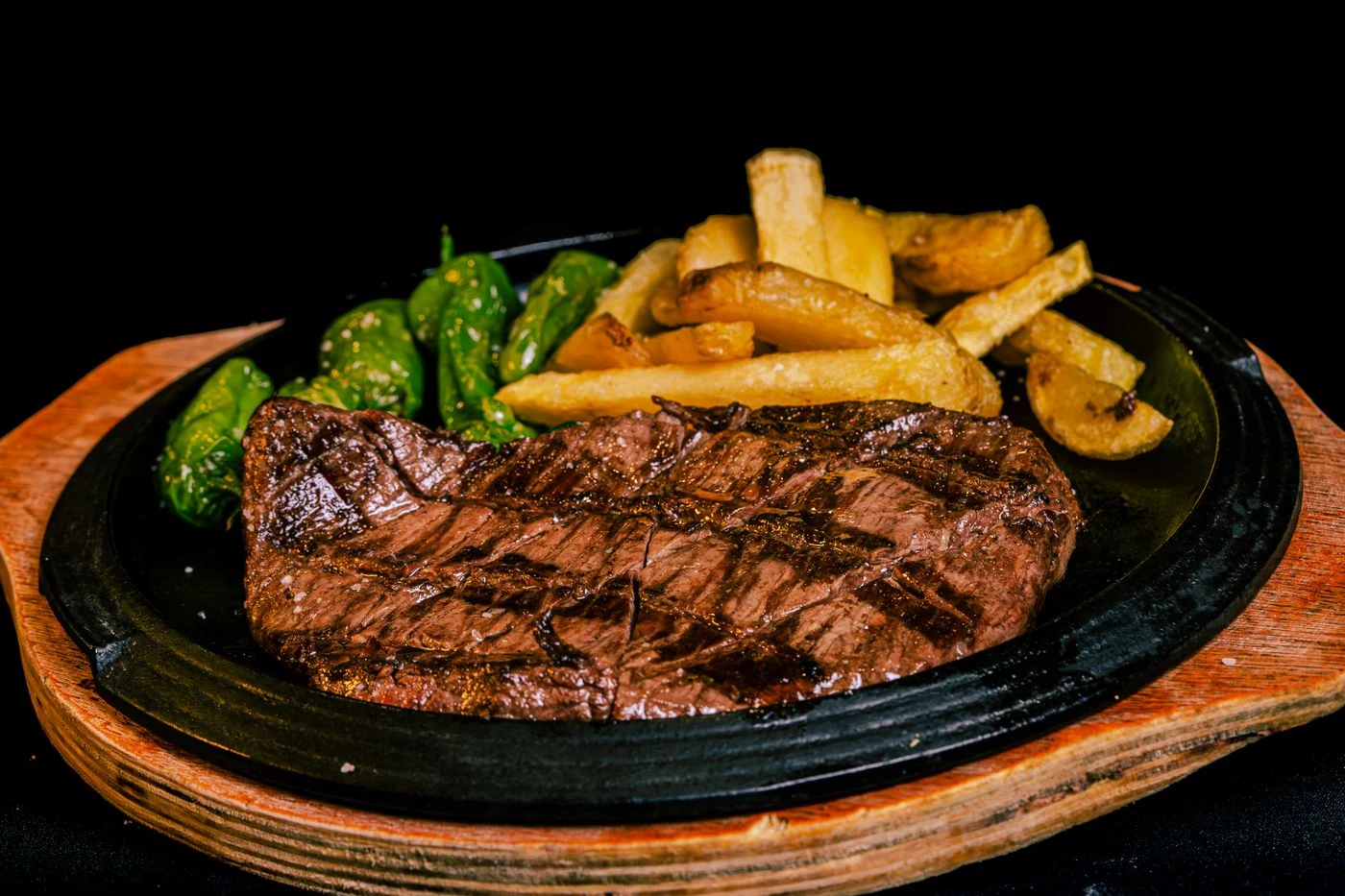 Bœuf grillé, frites dorées et petits poivrons. Photographie d’illustration.